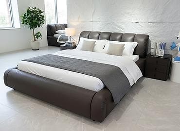 Двуспальная кровать с мягким высоким изголовьем и широким кожаным