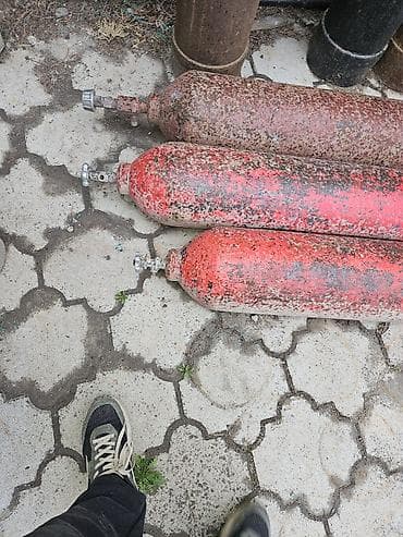 Синий газовый баллон цилиндрической формы. Оснащен запорным вентилем с