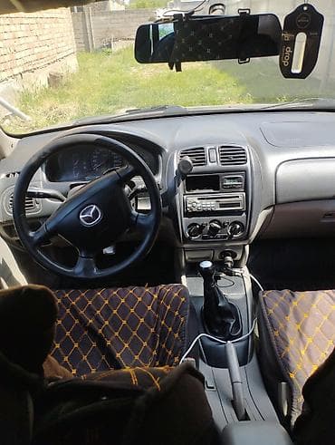 mazda primacy: Mazda — интерьер и оборудование салона - Рулевое колесо с эмблемой — 1