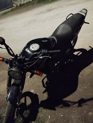 Мотоцикл дорожного типа, черный цвет. Классическая круглая фара