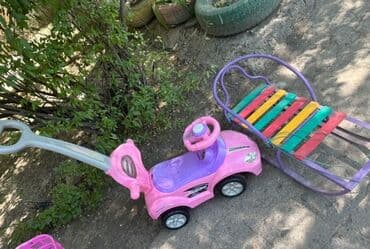 Детская машинка-каталка розового цвета с ручкой для толкания. Оснащена