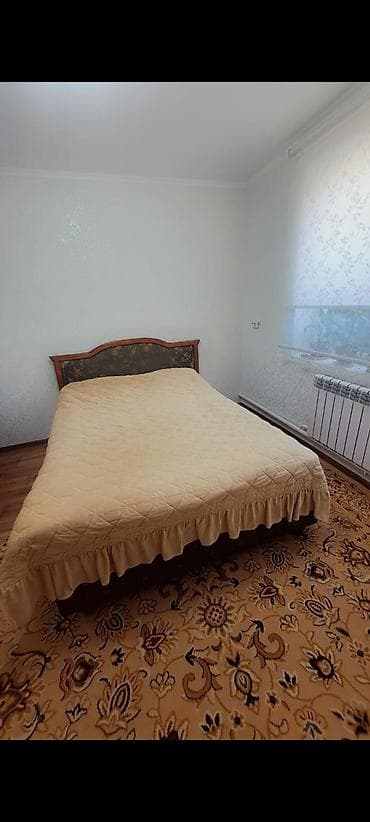 Двуспальная кровать с высокой мягкой спинкой и деревянной рамой