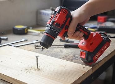 Аккумуляторная дрель-шуруповерт красно-черного цвета. Оснащена