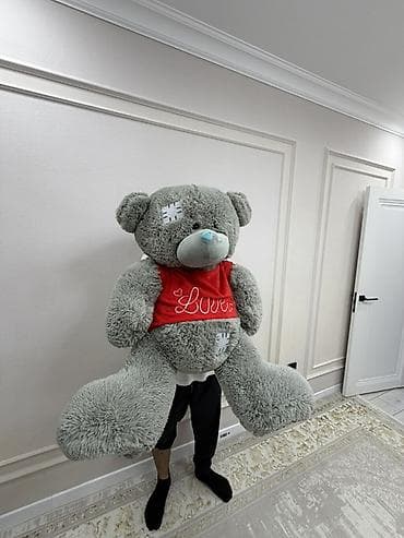 Большой плюшевый мишка-гигант, серого цвета, с голубым носиком. На