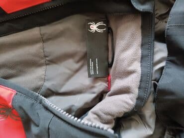 Платья: Детская лыжная куртка черного цвета с красными вставками. Оснащена — 3