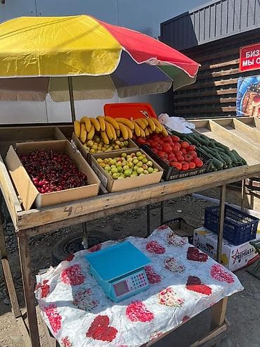 Уличная фруктово‑овощная витрина под зонтом Ассортимент на прилавке at lalafo.kg Уличная фруктово‑овощная витрина под зонтом Ассортимент на прилавке