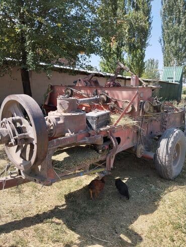 Прицепной пресс-подборщик красного цвета, предназначенный для сбора