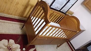 детскую кровать с люлькой: Деревянная детская кроватка светлого оттенка, оснащенная колесиками — 3