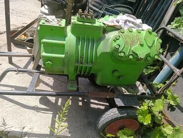 Промышленный компрессор зеленого цвета. Компрессор оснащен оребренными