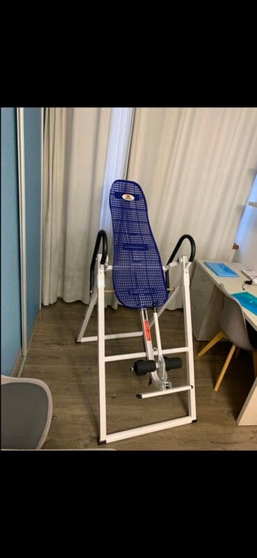 Инверсионный стол с белой рамой и синим сетчатым ложем. Оснащен