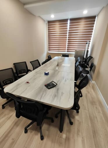 Просторный конференц-стол с серой столешницей под мрамор и черными