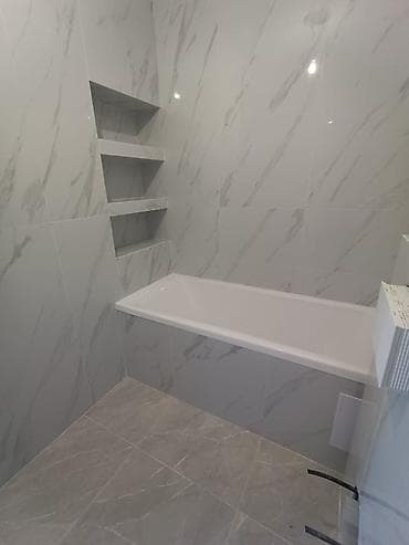 Ванная комната с облицовкой под мрамор и нишами для хранения. - Ванна