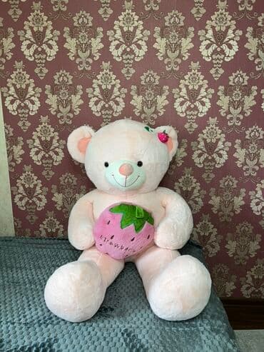 Большой мягкий плюшевый медведь нежного розового цвета. Держит в лапах