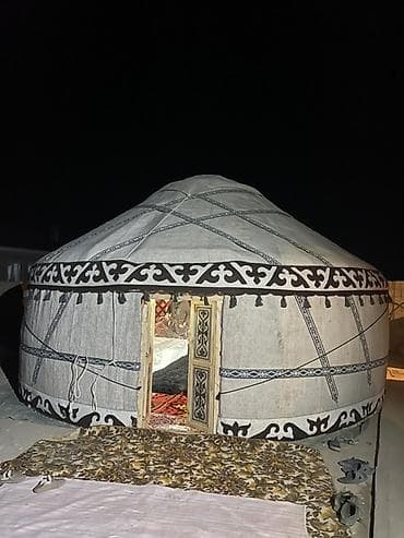 Традиционная юрта с белым внешним покрытием, украшенным черными