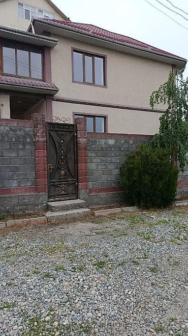 Двухэтажный дом с огороженным участком и коваными воротами угловое