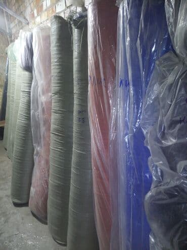 Рулоны ткани различных цветов, упакованные в прозрачную пленку для