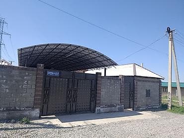 Дом с большим навесом и хозяйственными постройками на огороженном