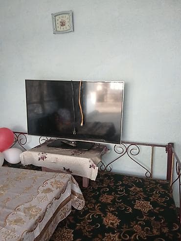 Телевизор с плоским экраном, диагональ примерно 50–55 дюймов. Черная