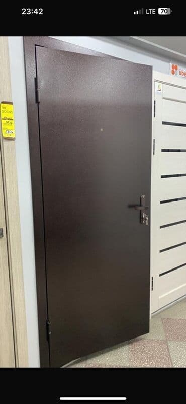 Металлическая входная дверь коричневого цвета. Оснащена дверной ручкой