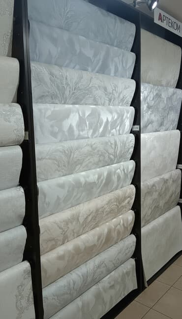 цена обоев за рулон: Рулоны обоев различных светлых оттенков, представленные на стенде — 1