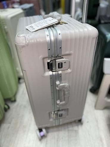 Чемодан с жестким корпусом светлого цвета, оснащенный четырьмя