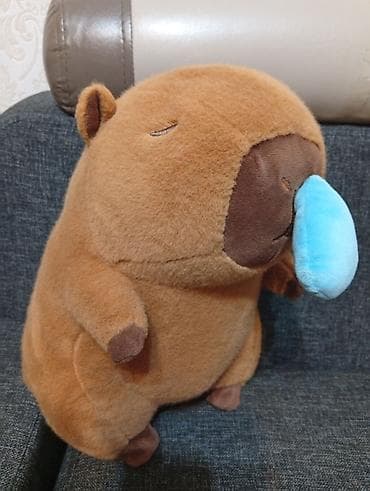 Плюшевая игрушка капибара с закрытыми глазами очень мягкая рядом с