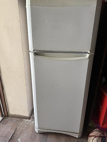 Холодильник двухкамерный, классический белый цвет. Верхняя камера —