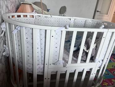 купить матрас на детскую кроватку: Эллиптическая детская кроватка белого цвета с вертикальными рейками — 1